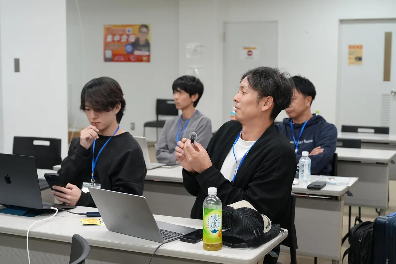 1日目の夕方、マイクを持って質問する参加者と、話を聞くほかの参加者